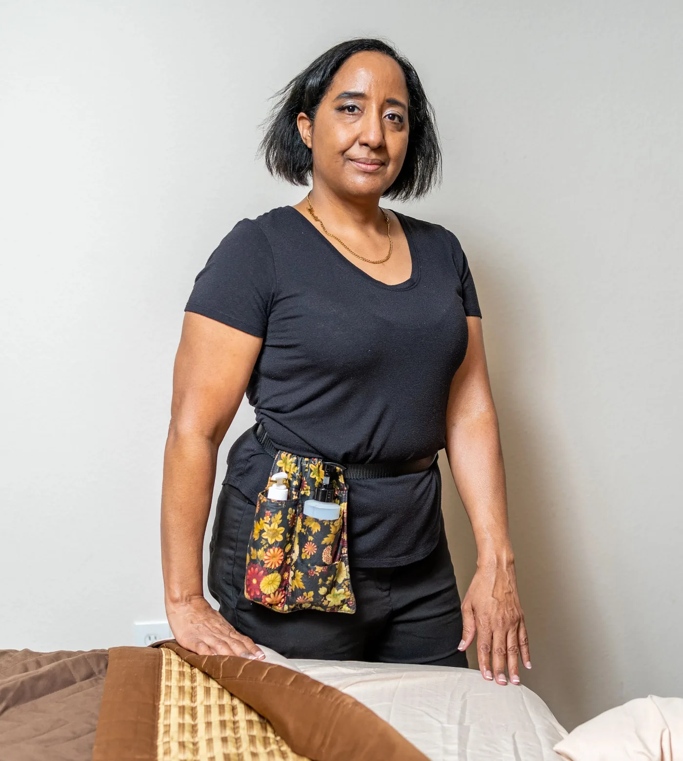 Nina Taylor standing beside her massage table in a client's home